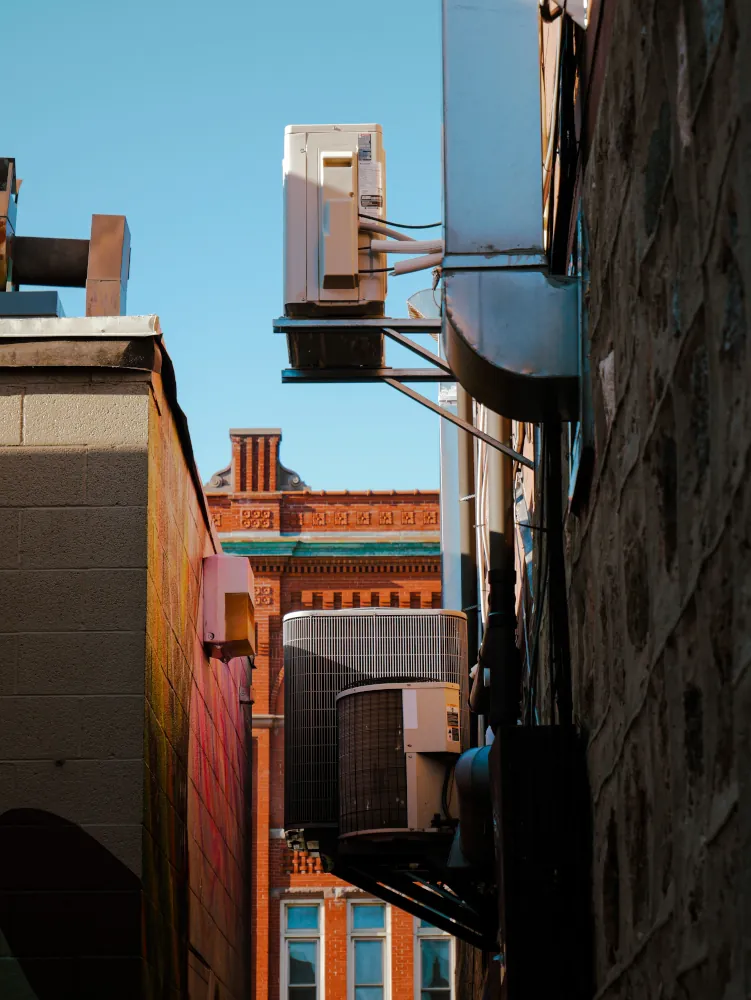 an outside air conditioner is seen in a narrow alley