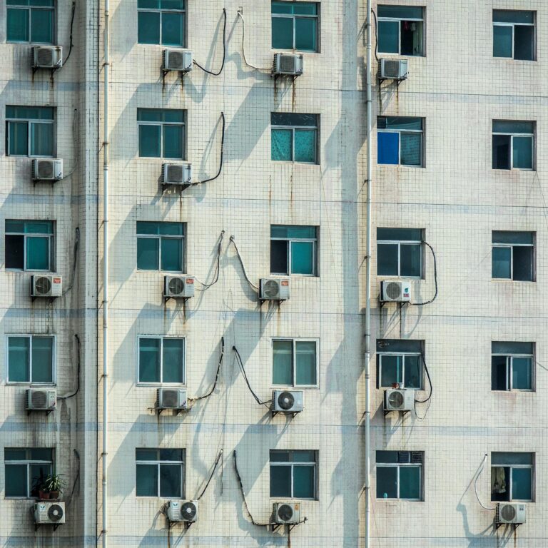 Urban residential building facade with air conditioning units on windows.